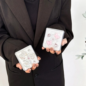 Detail shot of a pearlescent white square compact mirror with 3D resin butterfly and bow