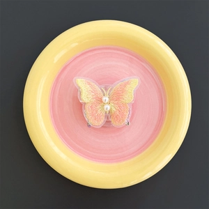 Detailed embroidery texture of pink butterfly phone grip with white pearl accents