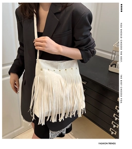 Dettaglio della borsa a tracolla boho con lunghe nappe crema e occhielli in metallo