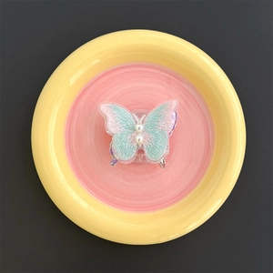 Detail of embroidered butterfly phone grip with soft pastel gradients and pearl accents