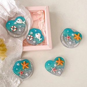 Detail view of heart-shaped resin phone grips with 3D dolphins, starfish and pearls