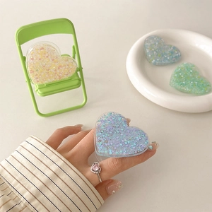Macro detail of heart-shaped phone grips with colorful glitter and sequins in various shades