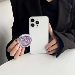 Detail view of purple heart phone grip with glitter and Gift For You text on white phone