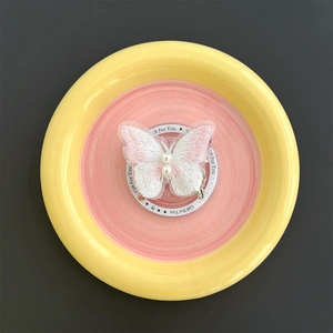 Detailed view of pink embroidered butterfly phone stand with pearls on gift packaging