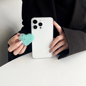 Detailansicht der mintgrünen Glitzer-Herz-Handyhalterung an einem weißen Smartphone