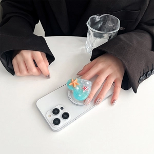 Detail of heart-shaped ocean blue phone grip with starfish and pearl on a white iPhone