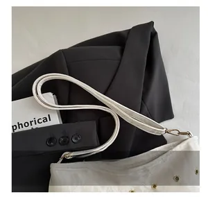 Dettaglio della borsa beige con occhielli in metallo e sottile tracolla regolabile