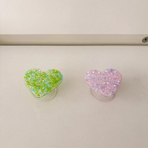 Detail of heart-shaped glitter phone grips in emerald green and pink purple sequins