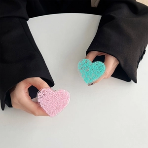 Detail von glitzernden herzförmigen Handyhaltern in Pink und Mintgrün aus Acryl