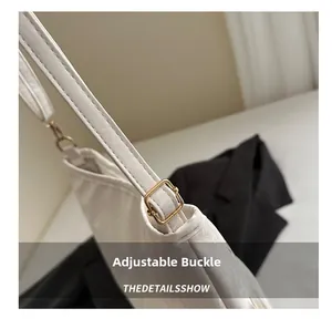Dettaglio della fibbia di regolazione dorata sulla tracolla in pelle color crema