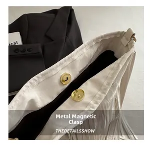 Dettaglio della chiusura magnetica in metallo su una borsa a tracolla boho con nappe