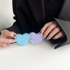 Detailansicht zweier Herz Glitzer Handyhalterungen in Lila und Blau gehalten in der Hand