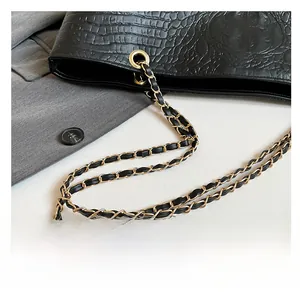 Detail of crocodile-embossed leather texture and gold-tone chain strap on black tote