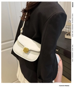 Gros plan d'un sac bandoulière blanc avec boucle dorée porté par un mannequin chic