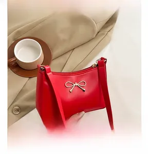 Detailed close-up of a red leather bag featuring a gold bow-knot metal buckle and texture