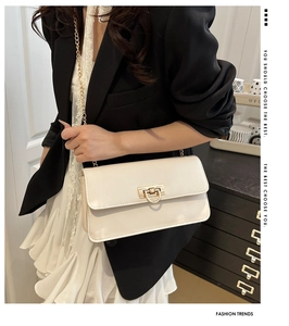 Sac bandoulière chic en cuir crème avec boucle dorée en D et chaîne sur mannequin