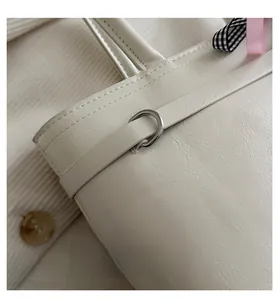 Makro-Detail der cremefarbenen Leder-Tasche mit Schleifen und silbernen Metallteilen