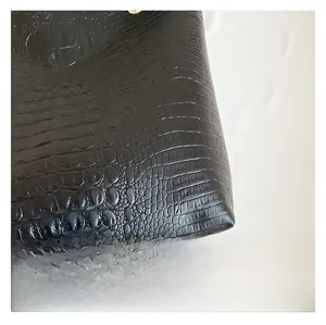 Close-up detail of high-quality black faux leather with crocodile embossed texture