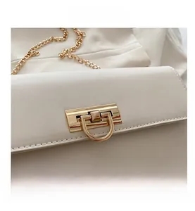 Vue détaillée du sac en cuir blanc avec boucle en métal doré et bandoulière chaîne