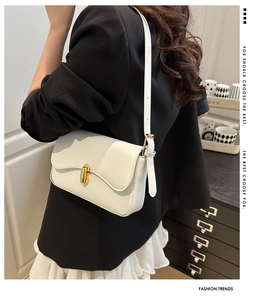 Detailed view of a white minimalist crossbody bag with elegant gold metal twist lock