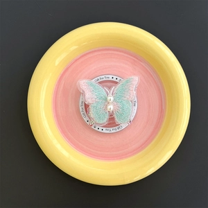 Detail of embroidered butterfly phone stand with pearl accents on a display card