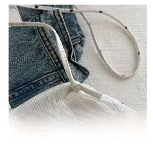 Detail of white pleated fabric with black floral pattern and thin shoulder straps