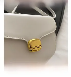 Détail de l'élégante boucle en métal doré sur un sac besace de couleur crème ivoire