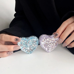 Detail of glitter heart phone sockets with blue and purple sequins held by a model