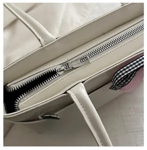 Details von glattem Metallreißverschluss und Ledertextur der cremefarbenen Tasche