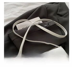 Gros plan du sac bandoulière blanc minimaliste avec fine sangle réglable et boucle dorée