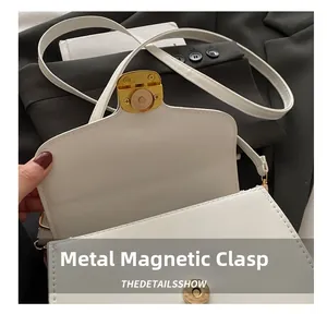 Gros plan sur le fermoir magnétique doré et le cuir blanc d'un sac bandoulière chic
