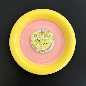 Top view of a yellow heart-shaped glitter phone socket on a pastel decorative tray