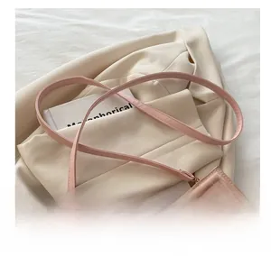 Detail of pink croc-embossed leather shoulder bag with adjustable gold metal buckle strap