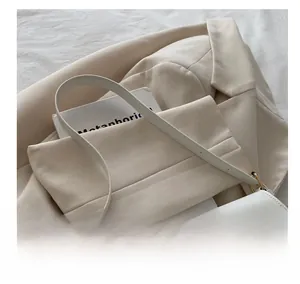 Detail of white minimalist shoulder bag featuring a golden metal rotary twist lock closure