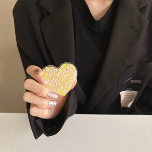 Detail of heart-shaped glitter phone grip with pink sequins on a black suit background