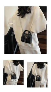 Detail view of mini black crossbody bag with chain strap and belt buckle decoration