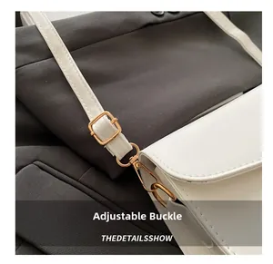 Détail de la boucle réglable en or champagne et du crochet sur la sangle blanche
