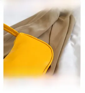 Close-up of bright yellow underarm bag showing precision stitching and smooth PU leather