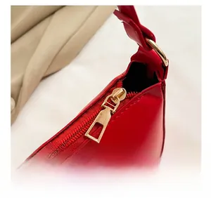 Detail of red glossy shoulder bag featuring gold metal zipper and stitching craftsmanship