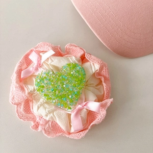 Detailed view of lace scrunchie with pink satin bows and sparkling green glitter heart