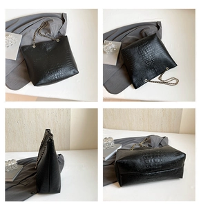 Detail of black tote bag with crocodile pattern texture and gold chain straps