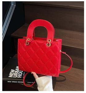 Detail view of red quilted crossbody handbag with gold hardware and top handle
