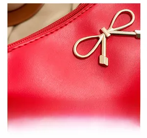 Detailed close-up of red leather handbag featuring a refined golden bow metal fastener