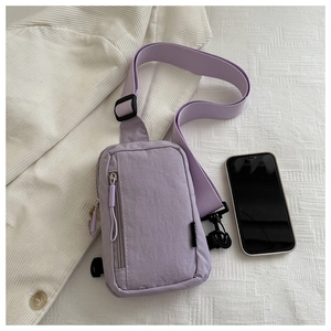 Detail view of light purple nylon chest bag with adjustable strap and phone for size reference
