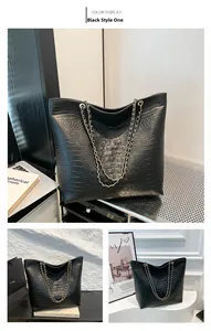 Detail of black crocodile embossed tote bag with elegant gold chain shoulder straps