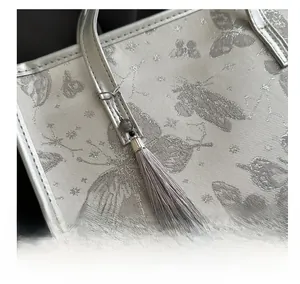 Detail of silver embroidery fabric butterfly pattern and purple tassel on tote bag