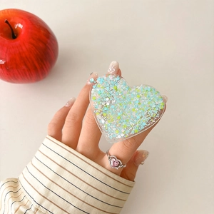 Macro shot of heart-shaped phone grip with blue glitter and sequins in hand