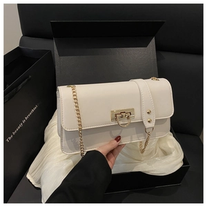Detail of a creamy white flap bag with gold chain strap and buckle in a premium gift box