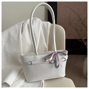 Détail du sac à main crème avec un nœud en ruban à carreaux roses et une boucle en métal