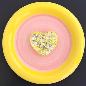 Macro detail of heart-shaped glitter phone stand with yellow and silver resin finish